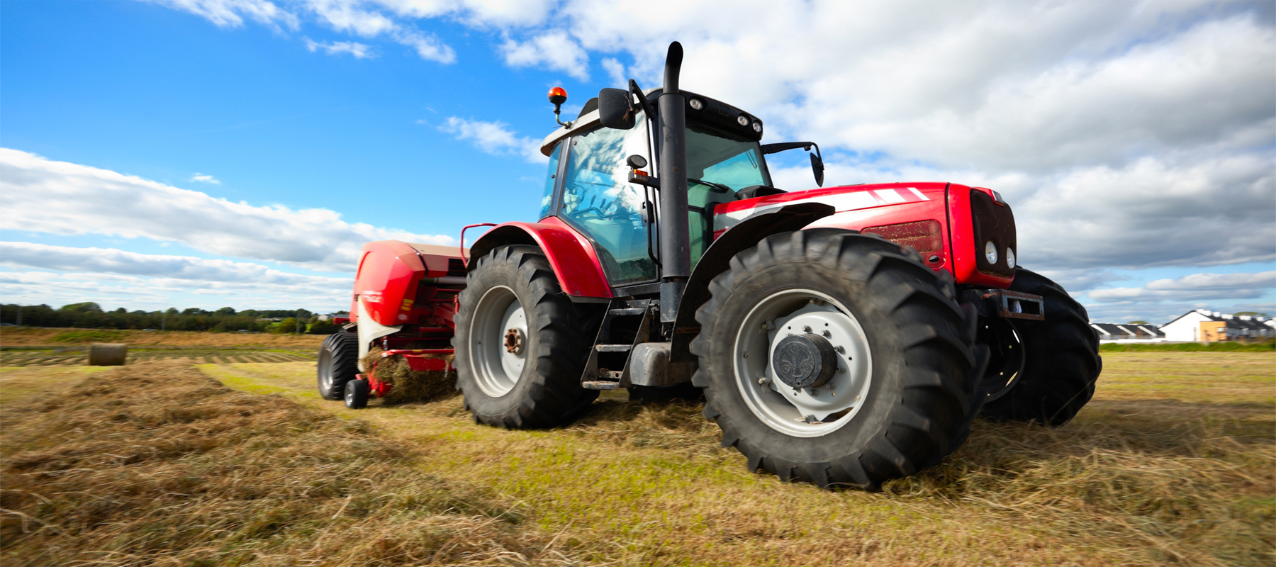 Large New Red Tractor Collecting Haystack in Field