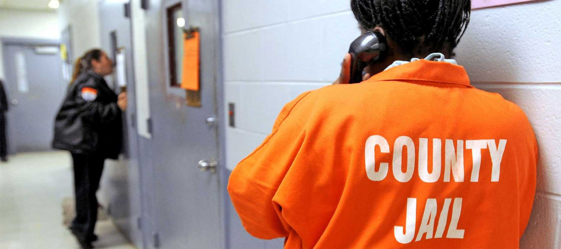 An Inmate in an Orange Suit Using a Prison Phone System
