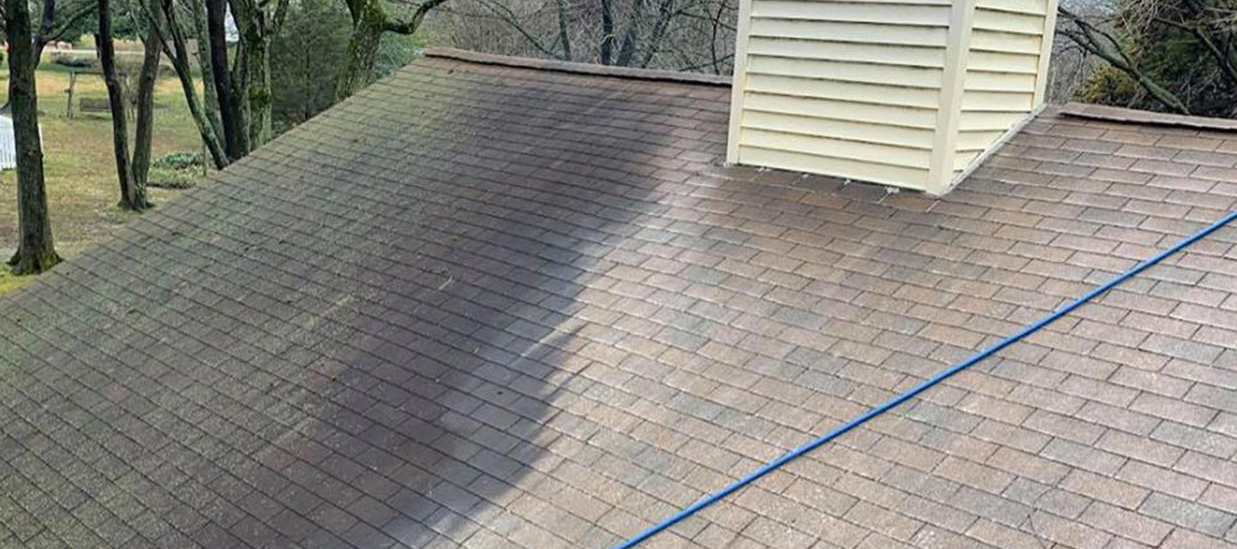 A Man on a Roof Doing a Pressure Wash Cleaning