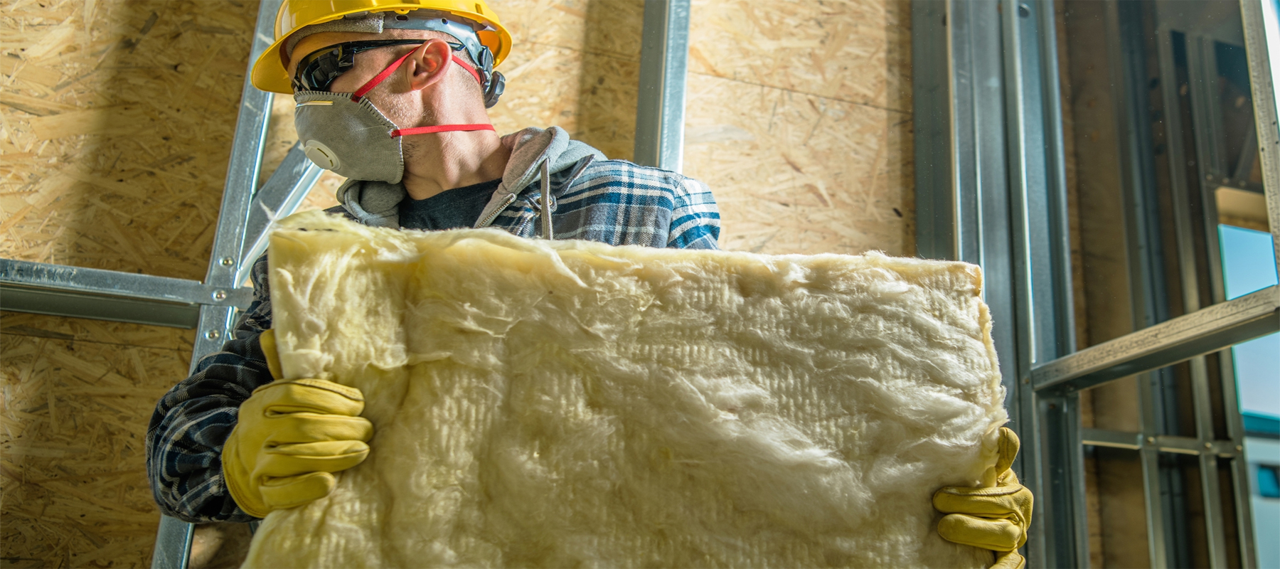 Worker Wearing Mask and Insulating a Steel Framed Building